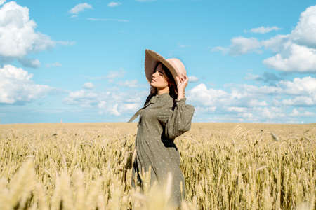 young woman in white dress, straw hat , flower field,ears of bread.の写真素材