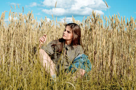 Beautiful girl model in dress in the countryside. Against the background of a field among wheatの写真素材