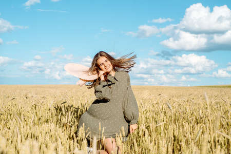 young woman in white dress, straw hat , flower field,ears of bread.の写真素材