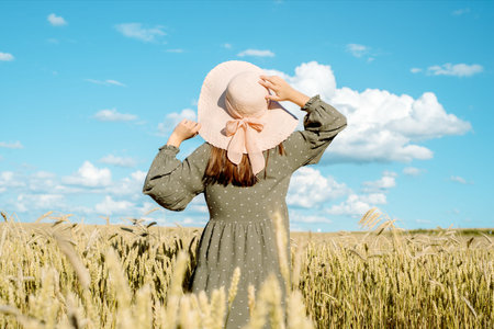 girl in a hat in a field with ears of corn on his back, summer harvest of bread. freedom concept