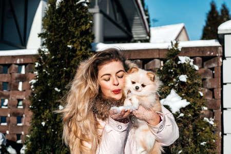 girl with a dog puppy spitz playing in winter outdoors funの写真素材