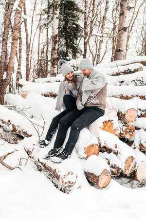 Cute couple in love sitting on the log, winter forest. Artwork.