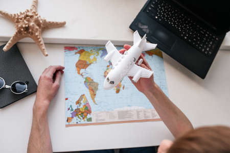 Travel concept. Young guy behind a laptop, work online, tourism and travel, globe and plane.の写真素材