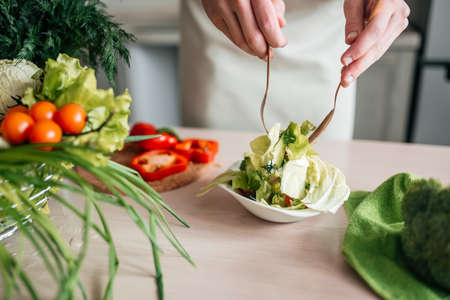 male hands chopping salad and onion, cooking healthy food in the kitchen.の写真素材