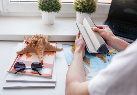 Travel concept. Young guy behind a laptop, work online, tourism and travel, globe and plane.の写真素材