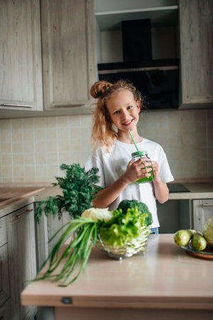 Portrait of cute little girl in the kitchen with green cabbage and broccoli, fresh vegetables and saladの写真素材