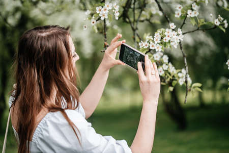 A girl with a phone in her hand takes pictures of selfies, photos for Internetの写真素材