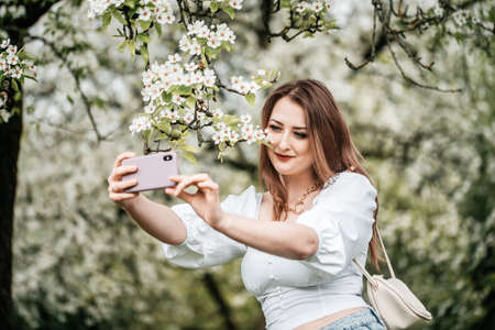 A girl with a phone in her hand takes pictures of selfies, photos for Internetの写真素材