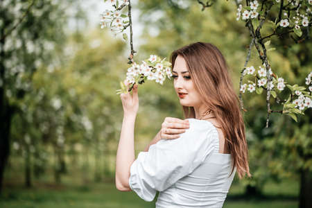 beautiful young blonde woman standing near the apple treeの写真素材