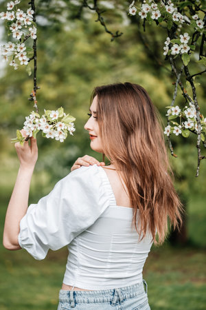 beautiful young blonde woman standing near the apple treeの写真素材