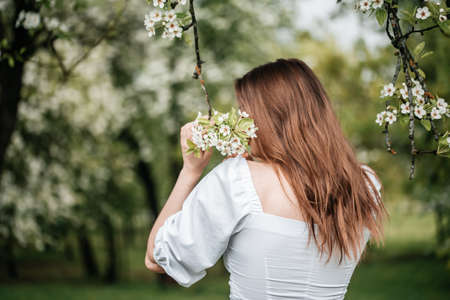 beautiful young blonde woman standing near the apple treeの写真素材