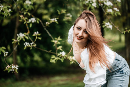 beautiful young blonde woman standing near the apple tree