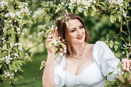beautiful young blonde woman standing near the apple treeの写真素材