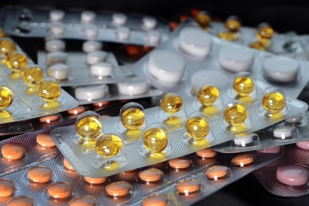 Yellow, white and orange medical tablets in pack, tablets and capsules and tablets packed in blisters. Full screen background. Healthcare and medical concept side view on black backgroundの写真素材