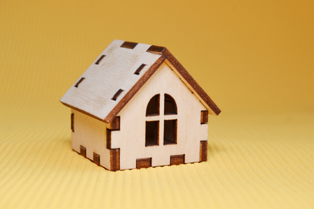 Wooden toy house model on yellow background, side viewの写真素材