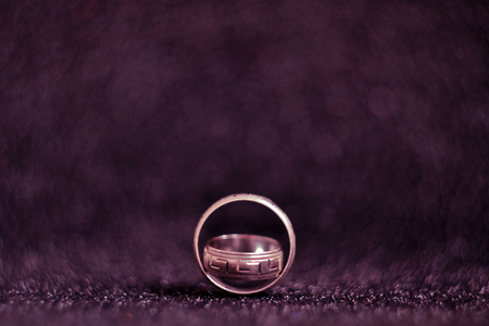 Two silver vintage wedding rings on a black and pink shiny surface, with a blurred background and copyspaceの写真素材