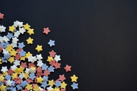 A lot of sugar colored stars on corner of black background macro, background for confectioners with...