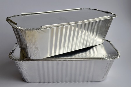 Two disposable ribbered foil food containers for takeaway on gray backgroundの写真素材