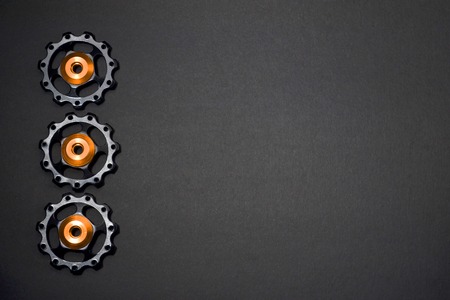 Color rollers, black, golden gears for bicycle rear derailleur on gray background in left side, with a copyspaceの写真素材