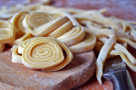 Twisted sliced dough and homemade pasta on boardの写真素材
