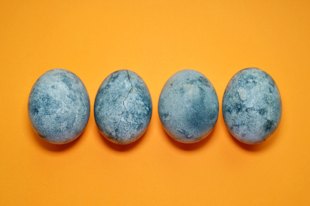 Four blue eggs, painted in a tea hibiscus, on orange background, similar to dragon eggs and marble with copyspaceの写真素材