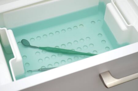 Dental mirror lies in blue fluid for disinfection. Instrument is decontaminatingの写真素材