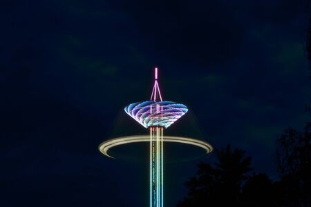 Attraction carousel on a long stock, multi-colored with light bulbs in night time, long exposure shootingの写真素材
