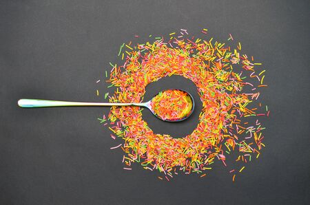 Long baking topping, sprinkled from a rainbow spoon in circle on gray background, decoration for bakery, top viewの写真素材