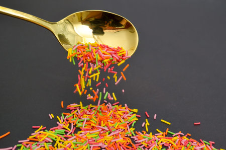 Long baking topping, sprinkled from golden spoon on a gray background