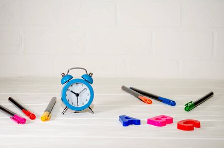 Blue retro alarm clock, ABC letters, colored pens lie on a white background with copyspace. School concept, study, knowledgeの写真素材