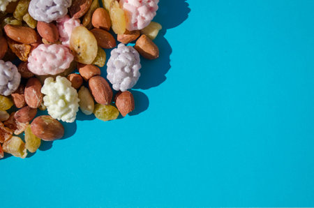 Assorted of sugared dried fruits, nuts and dragees in sugar, on a blue background with copyspace