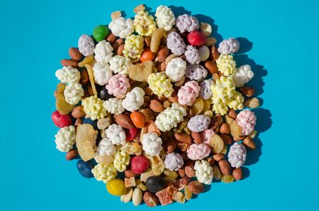 Assorted of nuts and dried fruits and dragees in sugar, in shape of circle, on a blue backgroundの写真素材