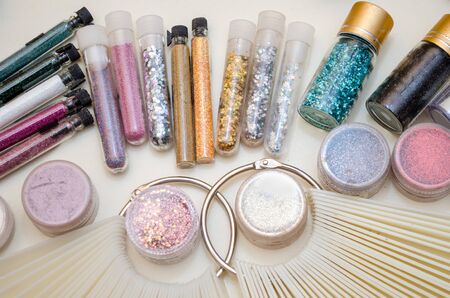 Jars with sparkles and decor for nail design, color samples of gel polish on a plastic tips closeupの写真素材