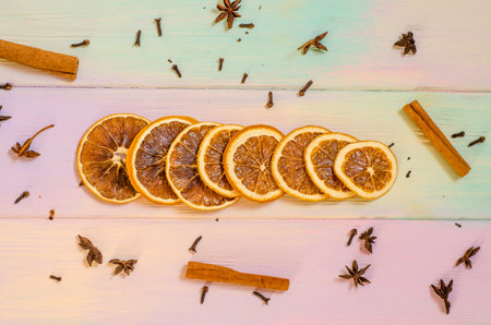 Set for mulled wine on a rainbow background, scattered dry oranges, cinnamon, cloves, star anise, with copyspaceの写真素材