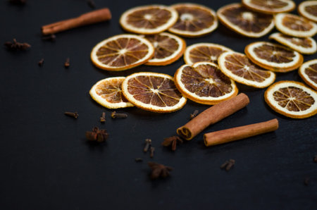 Set for mulled wine on a black background, scattered dry oranges, cinnamon, cloves, star anise, with...