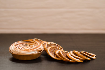 Delicious sweet orange tart with a baked top, black background with slices of dry fruit, as a background for holiday menus and postsの写真素材