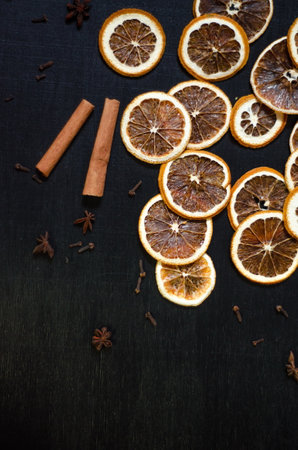 Set for mulled wine on a black background, scattered dry oranges, cinnamon, cloves, star anise, with copyspaceの写真素材