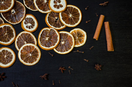 Set for mulled wine on a black background, scattered dry oranges, cinnamon, cloves, star anise, with copyspaceの写真素材