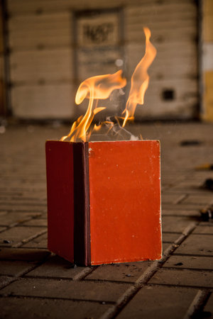 Paper book burns to ashes on concrete tiles, manuscript burns, open book with burning fireの写真素材