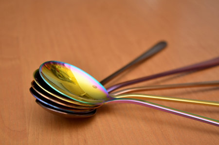 Multicolored table spoons on a plain wooden background, picture for an article about tableware or cutlery, with a copyspaceの写真素材