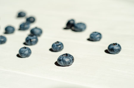 Fresh blueberry berries lie under the sunlight with shadows on a white wooden background. The topic of ecological, healthy and natural food, vegans. With copyspaceの写真素材