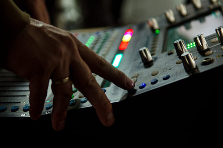 Hand of a music producer while working on a mixing desk at a rock band concert