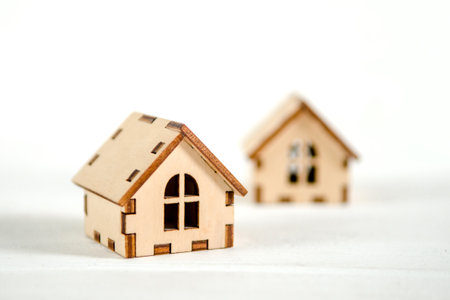Two small wooden houses on a white wooden background, the concept of family happiness, buying a houseの写真素材