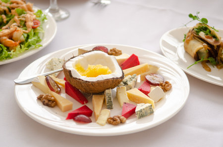 Dish in a restaurant, cheese slice on a white plate, in coconut, among other dishes on a white tableclothの写真素材
