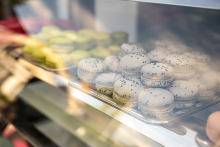Large amount of pink macaron dessert cakes in refrigerator with glass display case, reflection and glare of glass are visibleの写真素材