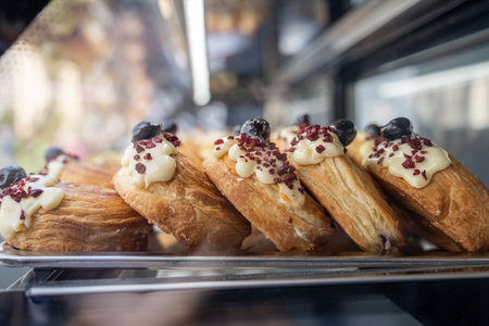 Puff pastry cake with cream and berries behind the glass display case of the refrigerator in cafeの写真素材