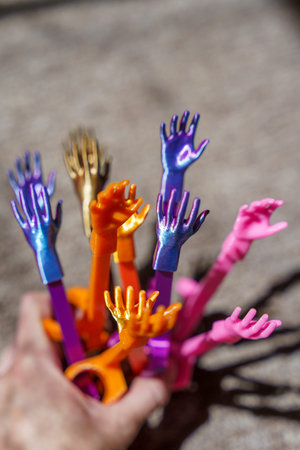 Colorful miniature plastic hands created with 3D printing technology raised upward together. Concept of participation, voting, teamwork, diversity or asking a question.の写真素材