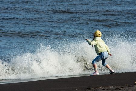 girl plays with wave ashore oceanの写真素材