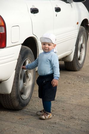 little boy touches wheel of the carの写真素材
