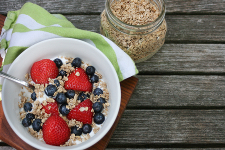 Healthy breakfast bowl. Granola in white bowl with greek yogurt and berries on wooden background, top view, copy space, horizontalの写真素材